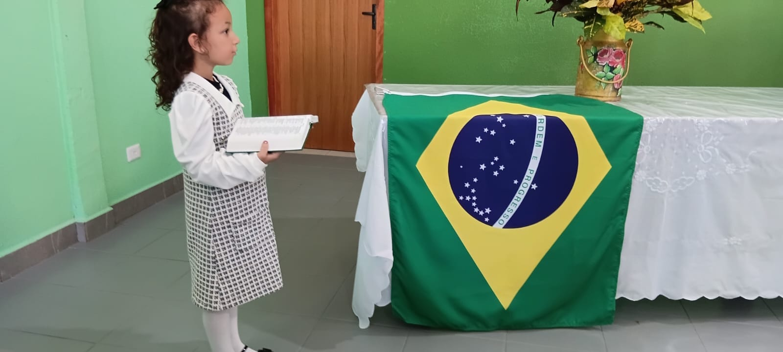 Criança lendo a Bíblia diante da bandeira do Brasil